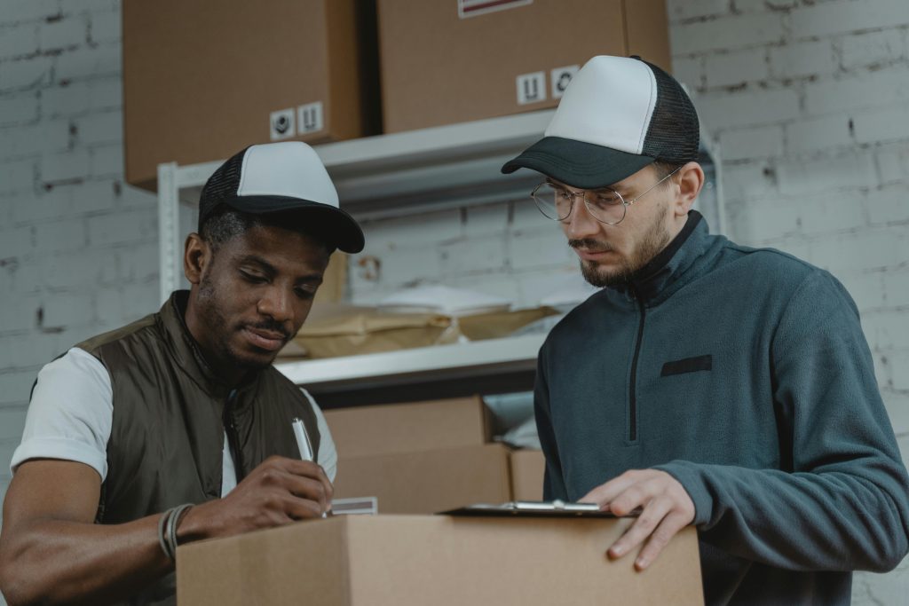 pexels-photo-6170089-6170089 Two couriers working together to process deliveries in a warehouse setting.